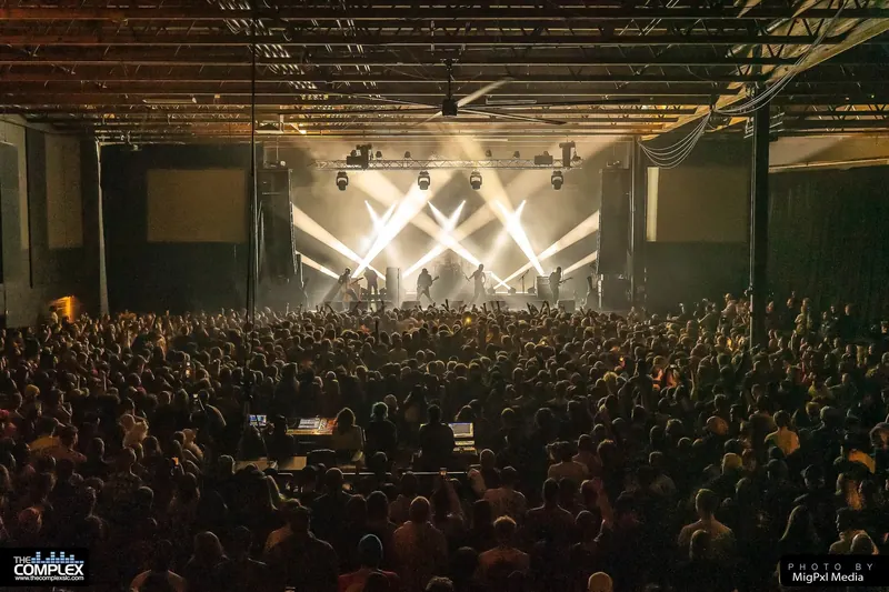 A sold-out crowd facing a lit stage at The Complex, a concert venue in Salt Lake City